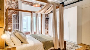 A bedroom with a brick wall, a canopy bed, and a wardrobe. - Central City 2bed With Mountain Views Skywood Loft (Cape Town)