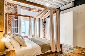 Ein Schlafzimmer mit Ziegelwand, Baldachinbett und Kleiderschrank.