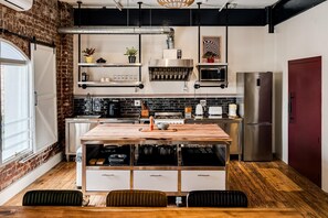A modern kitchen with a central island, stainless steel appliances, and a brick wall. - Central City 2bed With Mountain Views Skywood Loft (Cape Town)