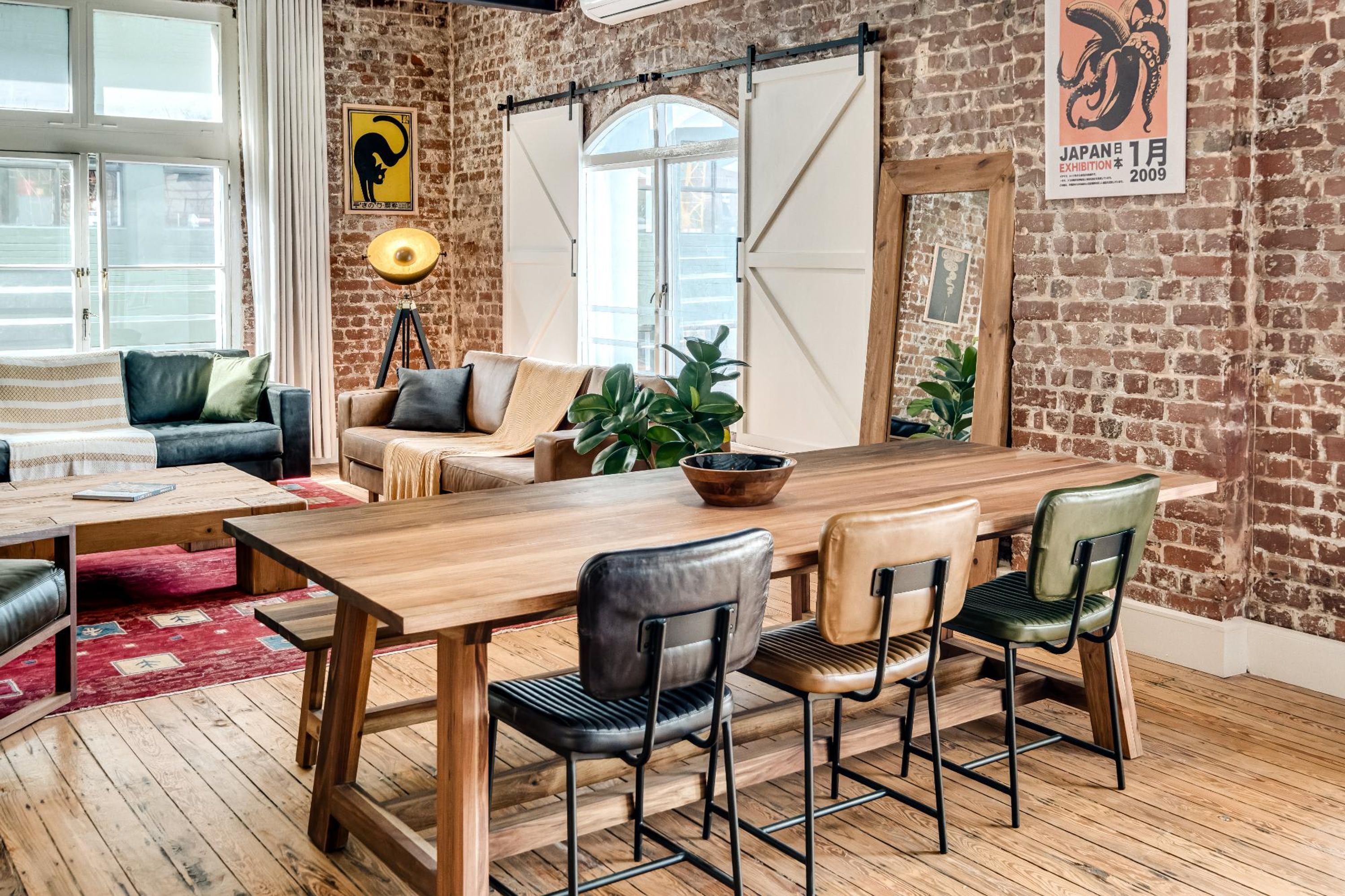 Um quarto acolhedor com uma mesa de jantar de madeira, quatro cadeiras, um sofá e um abajur.