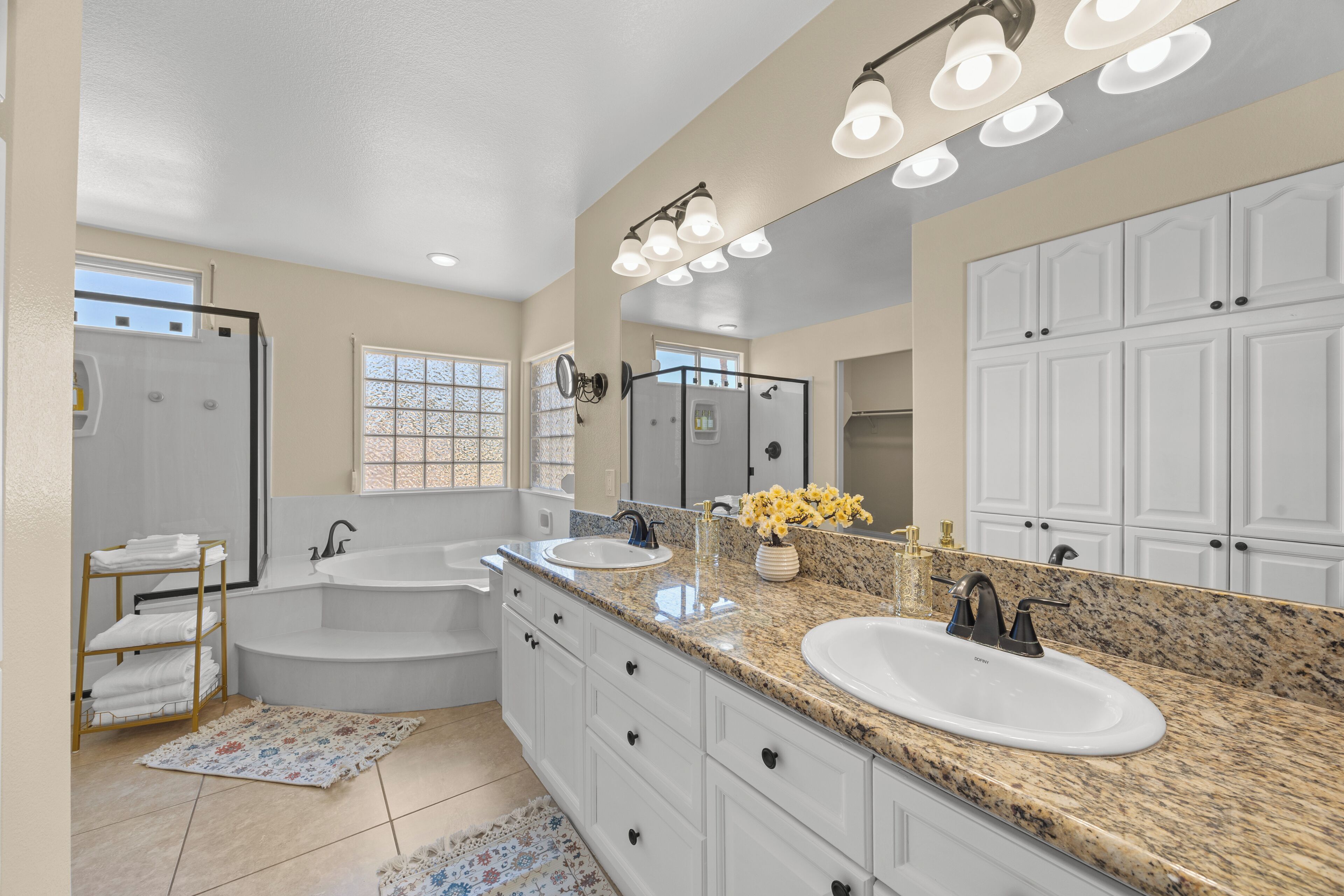 A modern bathroom with a double sink vanity, a large mirror, a walk-in shower, and a bathtub.