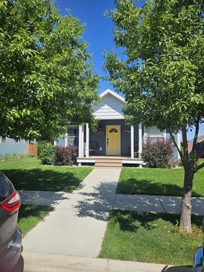A residential house with a front porch, a yellow door, and a mailbox. - Sunny Threshold
Spacious 4-bedroom house in quaint Helena with cool AC (Helena)