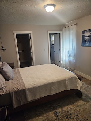 A bedroom with a bed, a door, a window with curtains, and a ceiling light. - Sunny Threshold
Spacious 4-bedroom house in quaint Helena with cool AC (Helena)