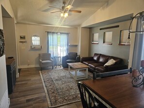 A living room with a brown leather sofa, a small round table, a grey armchair, and a patterned rug. - Sunny Threshold
Spacious 4-bedroom house in quaint Helena with cool AC (Helena)