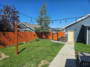 A residential backyard with a wooden fence, a pathway, and a house with a yellow door. - Sunny Threshold
Spacious 4-bedroom house in quaint Helena with cool AC (Helena)