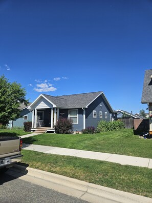 Ein Wohnhaus mit Veranda, Garage und gepflegtem Rasen.