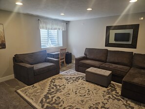 A living room with two sofas, a coffee table, a rug, a TV, and a window with blinds. - Sunny Threshold
Spacious 4-bedroom house in quaint Helena with cool AC (Helena)