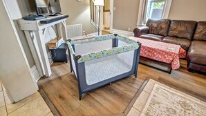 Ein Wohnzimmer mit einem Babyreisebett, einem Ledersofa, einem Fernseher und einem Kamin.