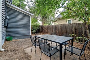 A patio with a table and chairs, surrounded by a wooden fence and trees. - Walnut Porch! Cozy Historic Home Near OCC (Colorado Springs)
