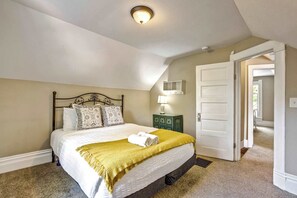 A bedroom with a bed, a bedside lamp, a door, and a ceiling light. - Walnut Porch! Cozy Historic Home Near OCC (Colorado Springs)