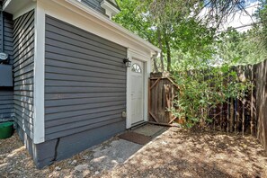 A residential building with a grey siding exterior, a white front door, and a wooden fence. - Walnut Porch! Cozy Historic Home Near OCC (Colorado Springs)