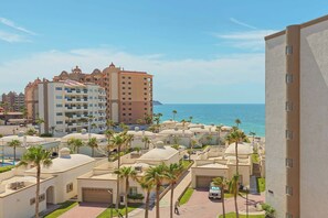 Ein Hotelkomplex an der Küste mit mehreren Gebäuden, Palmen und freiem Blick auf das Meer.