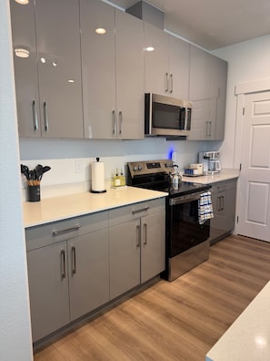 A modern kitchen with grey cabinets, a stainless steel oven, a microwave, and a coffee maker.