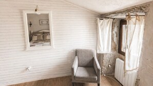 A room with a single armchair, a mirror, and a window with curtains.