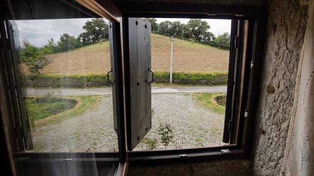 A window with a view of a rural landscape, including a road and fields. - Schist Houses - Casa da Capela (2-Bedroom House) (Bragança)