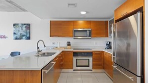Una cocina moderna con armarios de madera, electrodomésticos de acero inoxidable y encimera blanca.