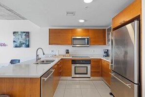 A modern kitchen with wooden cabinets, stainless steel appliances, and a white countertop. - Top Modern 2BR in Miami - Best location ever! (Miami)