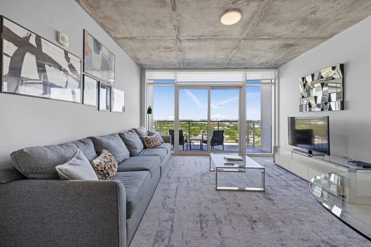A modern living room with a grey sofa, a coffee table, and a flat-screen TV.