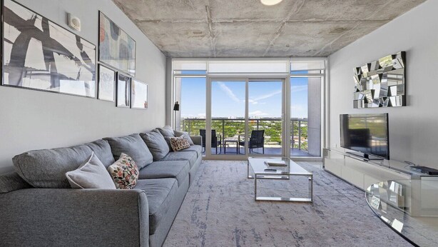 Una sala de estar moderna con un sofá gris, una mesa de centro y un televisor de pantalla plana.