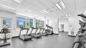 Uma academia com esteiras, bicicleta ergométrica e remo.