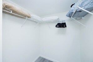A white room with a built-in closet containing hanging clothes and a storage bench. - Brickell brand new unit 26th floor (Miami)