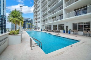 A swimming pool with a white building and balconies in the background. - Brickell brand new unit 26th floor (Miami)