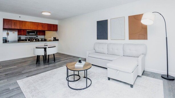Una sala de estar moderna con un sofá blanco, una mesa de centro redonda y un comedor con una mesa y sillas blancas.