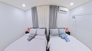 Une chambre d’hôtel avec deux lits, un ventilateur de plafond, un appareil de climatisation et une fenêtre avec des rideaux.