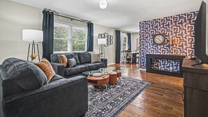 A living room with a sofa, coffee table, and a patterned wall. - The Mod Maze | 2 Kings • Fireplace • Central OMAHA (Omaha)