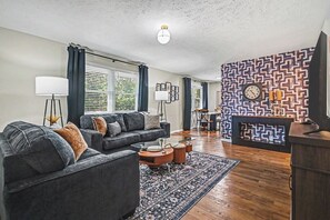 A living room with a sofa, coffee table, and a patterned wall. - The Mod Maze | 2 Kings • Fireplace • Central OMAHA (Omaha)