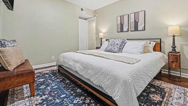 A bedroom with a bed, bedside tables, a chair, and a rug. - The Mod Maze | 2 Kings • Fireplace • Central OMAHA (Omaha)