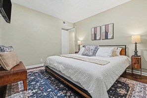 A bedroom with a bed, bedside tables, a chair, and a rug. - The Mod Maze | 2 Kings • Fireplace • Central OMAHA (Omaha)