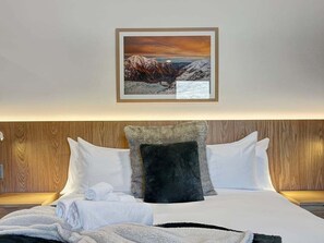 A hotel room with a bed, pillows, a blanket, and a framed picture on the wall. - Above the Lake | Studio Escape (Queenstown)