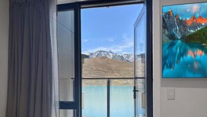 Ein Zimmer mit einer großen Glasdoor, die auf einen Balkon mit Bergblick und Seeblick führt.