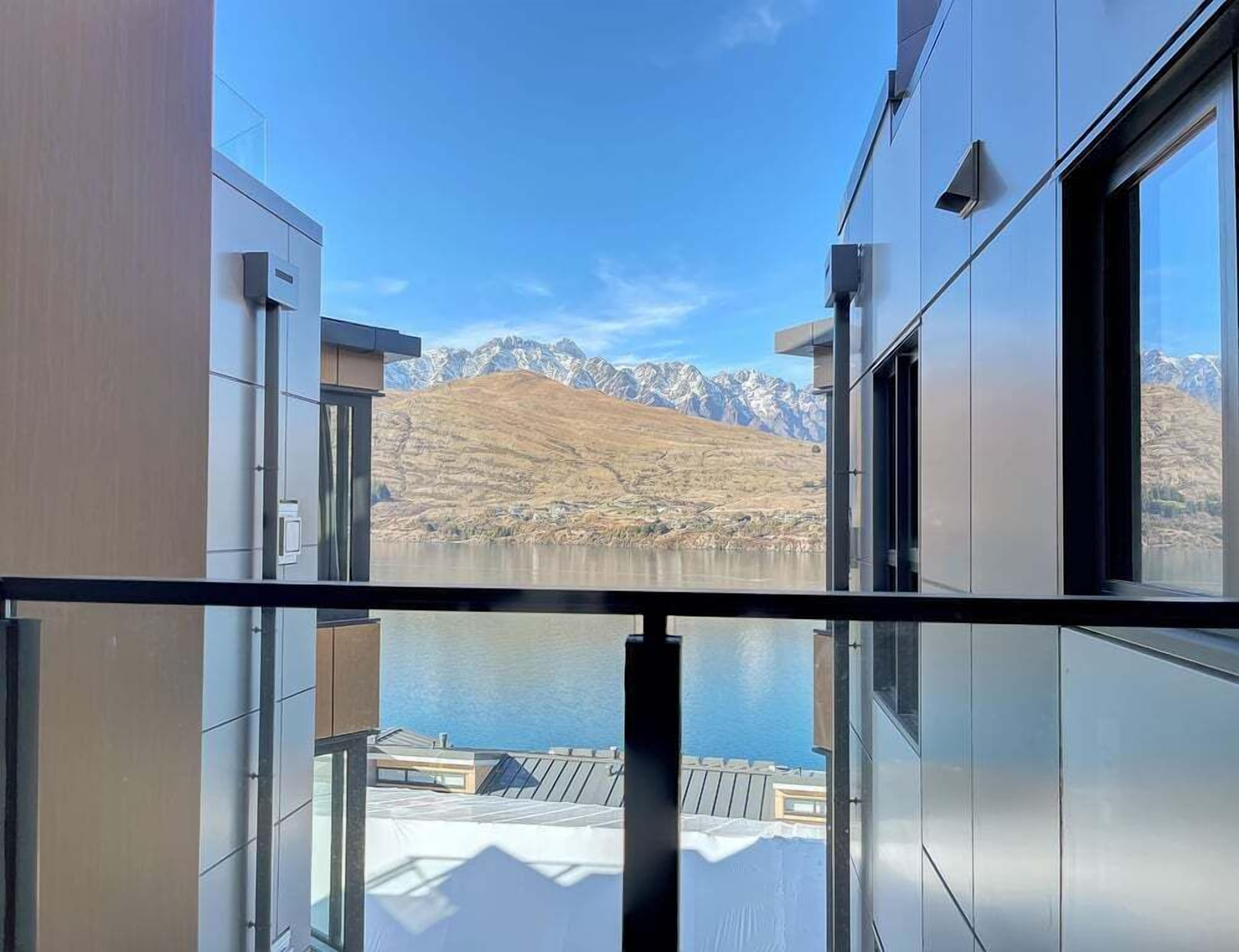 A modern building with large windows overlooking a mountainous landscape and a body of water.