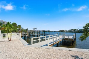 A waterfront dock with a white railing, calm water, and a clear blue sky. - IRB Coastal Escape, 5BR All En-Suite, Pool & Dock (Indian Rocks Beach)