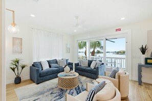 A modern living room with two sofas, a coffee table, and a view of the water. - IRB Coastal Escape, 5BR All En-Suite, Pool & Dock (Indian Rocks Beach)