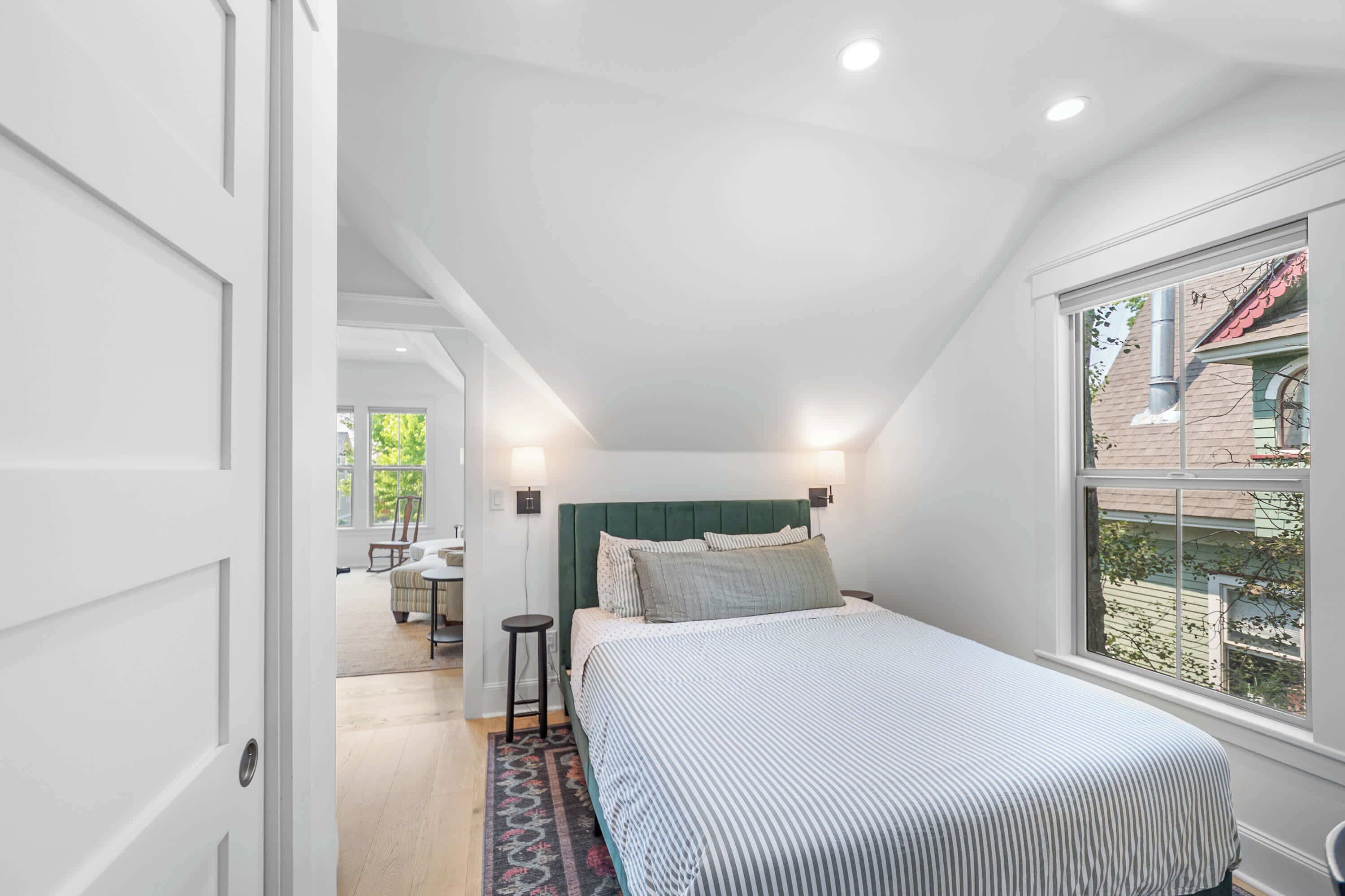 Een slaapkamer met een bed, nachtlampen, een raam en uitzicht.