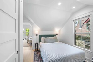 Ein Schlafzimmer mit Bett, Nachttischlampen, einem Fenster und Blick ins Freie.