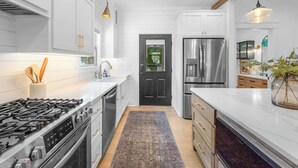 A modern kitchen with white cabinetry, stainless steel appliances, and a central island. - Northern Charm with 3BDR & Game Room (Kalispell)