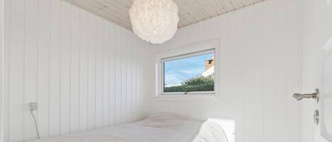 A bedroom with a single bed, a window, and a door.