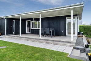 A modern building with a covered patio area, a seating arrangement, and a well-maintained lawn. - Cosy holiday home near Kerteminde (Kerteminde)