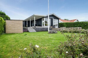 A modern house with a covered porch, a stone wall, and a well-maintained lawn. - Cosy holiday home near Kerteminde (Kerteminde)