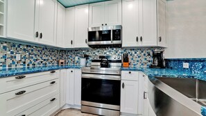 Una cocina moderna con armarios blancos, estufa de acero inoxidable y microondas.