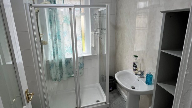 Un baño moderno con ducha envuelta en vidrio, un lavamanos blanco y un inodoro.