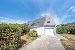 A residential house with a garage, a driveway, and a well-maintained lawn. - Votre cocon breton • Calme & Jardin (Quéven)