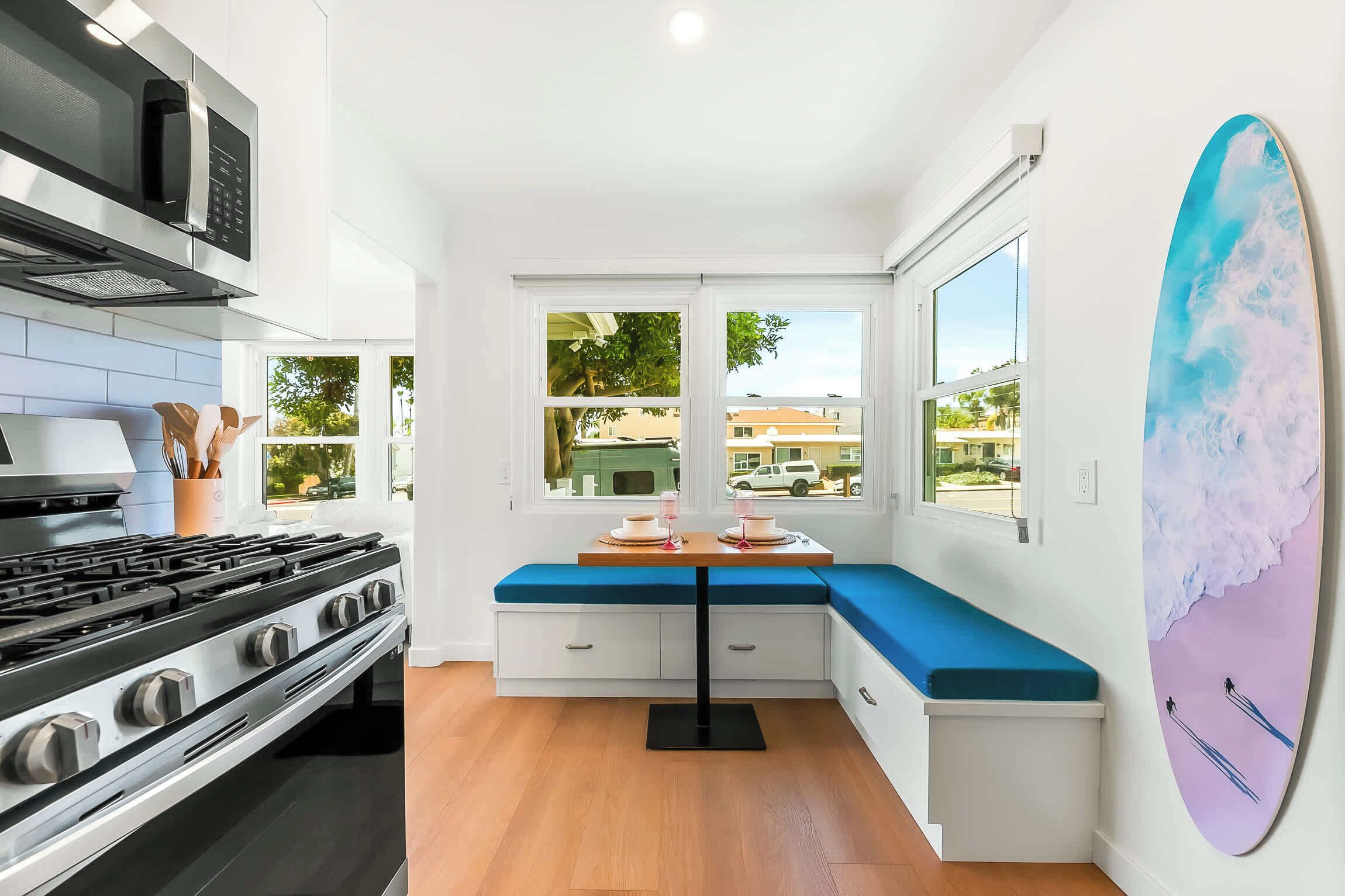 A compact kitchen with a gas stove, a microwave, and a large window offering a view of the neighborhood.