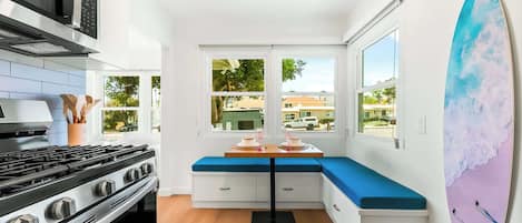 A compact kitchen with a gas stove, a microwave, and a large window offering a view of the neighborhood.
