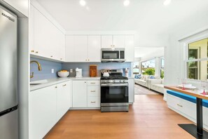 A modern kitchen with white cabinets, a stainless steel oven, and a microwave. - The Tourmaline Beach House - Walk to Surf & Sand (San Diego)