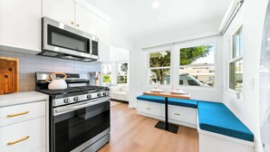 Une cuisine moderne avec des meubles blancs, un four encastré, une cuisinière et un four à micro-ondes.